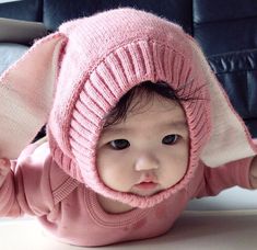 a baby wearing a pink sweater and hat with an elephant ears on it's head