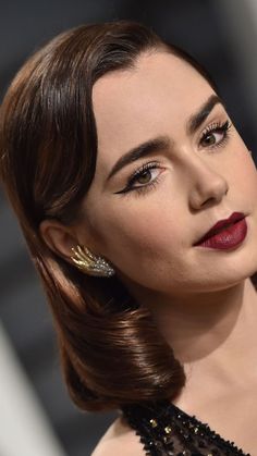 a close up of a woman with dark hair and red lipstick wearing an elegant dress