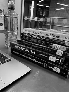 a laptop computer sitting on top of a desk next to books and a water bottle