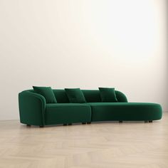 a green couch sitting on top of a hard wood floor next to a white wall