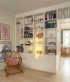 a living room filled with lots of white bookshelves next to a wooden floor