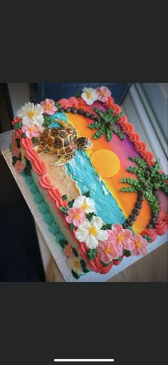 there is a cake decorated with flowers and a turtle on the beach