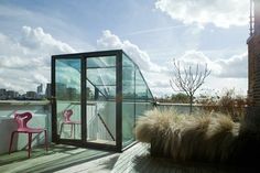 a pink chair sitting on top of a wooden floor next to a tall glass building