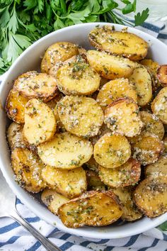 a white bowl filled with potatoes covered in parmesan sprinkled seasoning