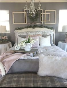 a white bed topped with pillows and blankets next to a chandelier filled with flowers