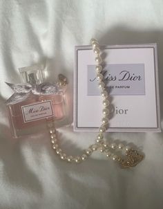 a bottle of perfume next to a box with a necklace on it and a card