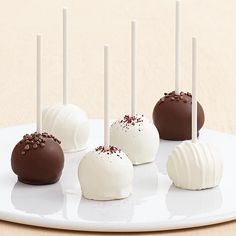 six chocolate covered cake pops on a white plate