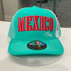 a turquoise mexico trucker hat with the word mexico on it sitting on a table