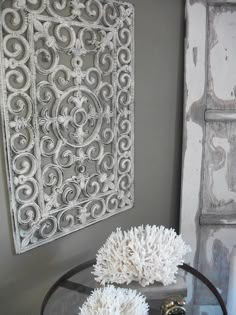 two white vases sitting on top of a glass table in front of a wall