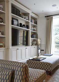 a living room with bookshelves and couches in front of a large window