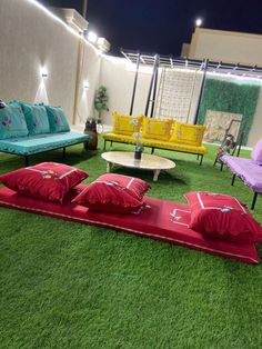 an outdoor area with couches, tables and chairs on artificial grass in the evening