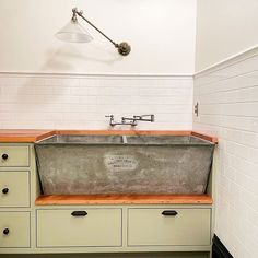 an old fashioned kitchen sink with wooden counter tops and drawers in the corner, under a light fixture