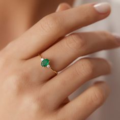 a woman's hand with a ring on it and a green stone in the middle