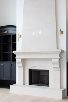 a white fireplace in a living room next to a black bookcase and cabinet with doors