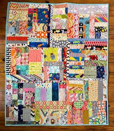 a quilt made with colorful fabrics on a wooden floor