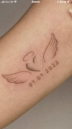 a small tattoo on the arm of a woman with a heart and wings in it