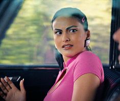 a woman sitting in the back seat of a car with her hand on her hip