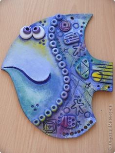 this is an image of a fish made out of paper and glue on wood board