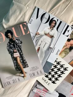 three magazines laying on top of each other next to a white sheet covered bedding