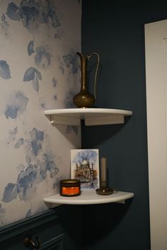 two shelves in a bathroom with blue and white wallpaper on the walls behind them