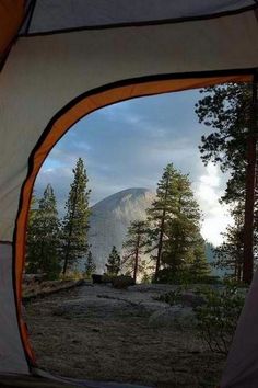 the view from inside a tent looking at trees and mountains