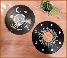 two black plates sitting on top of a wooden table next to a potted plant