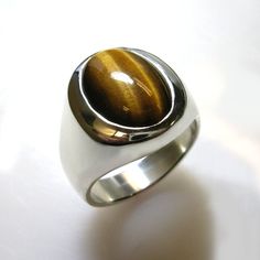 Masculine elegance. A truly stunning ring. Our own unique spin on a smart looking, timeless classic. We use finest quality, rare, Tiger Eye in a specially cut high dome that shows more stone which creates a unique and striking effect. This ring is solid- not hollowed out underneath which gives it a substantial value and weight and nicer feel and weighs from approx. 24 to 30 grams depending on the ring size. Truly looks great on a a wide range of finger sizes. (pictured on a size 10 ring finger) Tigers Eye Ring, Tiger Ring, Tiger Eye Ring, Brown Stone, Eye Ring, Tiger's Eye, Size 10 Rings, Ring Finger, Timeless Classic