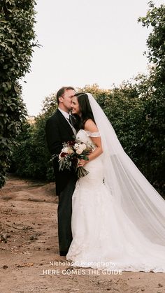 a bride and groom standing in front of some trees