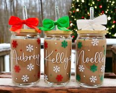 three decorated mason jars sitting on top of a wooden table next to a christmas tree