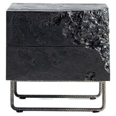 a black marble side table with metal legs and an intricate design on the top, in front of a white background