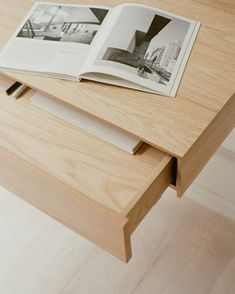 an open book sitting on top of a wooden table next to a drawer with drawers