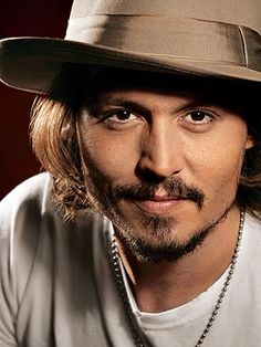 a man with long hair and a beard wearing a fedora is looking at the camera