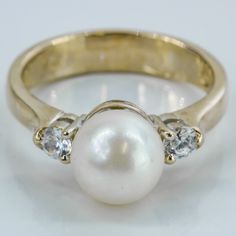 a pearl and diamond ring on a white surface