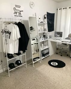 a bedroom with white walls and carpeted flooring, clothes hanging on racks in the corner