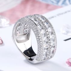 Celebrate your everlasting love story with this elegant band. Stunning as a wedding or anniversary band, two rows of sparkling round stones are set across the center of this band and split by a row of smaller round stones - decorates the ring's impressive shank. A double row of smaller round stones grace the top and bottom of the band, completing this exceptional design. This band is a beautiful reminder of your timeless romance.Carat Weight: 6.575 ctStone Size: 3,1,1.2 mmStone Type: Jeulia® Sto Formal Rings With Rhinestones, Classic Rhinestone Jewelry For Anniversary, Classic Rings With Bling For Anniversary, Cubic Zirconia Half Eternity Jewelry For Marriage, Wedding Diamond Ring With Rhinestones, Cubic Zirconia Bands With Diamond Accents, Classic Anniversary Ring With Bling, Classic Anniversary Rings With Bling, Silver Cubic Zirconia Eternity Band For Wedding