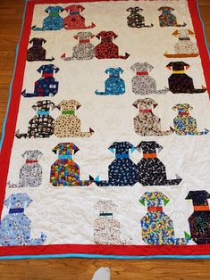 there is a quilt on the floor that has many dogs in different colors and sizes