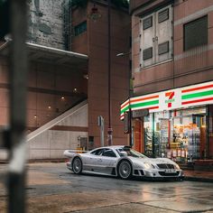 a silver sports car parked in front of a store