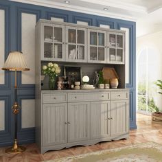 a living room with blue and white walls, a large china cabinet in the center