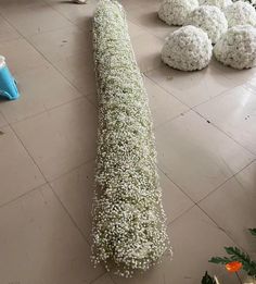 white flowers are arranged on the floor in front of a long piece of grass that has been cut into smaller balls