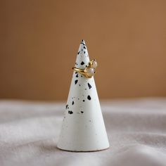 a small white ceramic christmas tree with black spots on it's top and gold accents