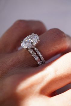 a woman's hand with a diamond ring on top of her finger and an engagement band