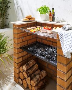 an outdoor bbq grill with lots of food cooking on top of it and logs stacked in front of it