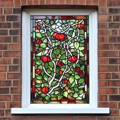 a stained glass window with apples and leaves in the center on a brick building wall