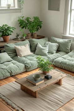 a living room filled with lots of green couches and pillows on top of a wooden floor