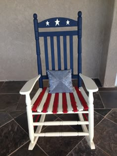 a red, white and blue rocking chair with a pillow on it's seat