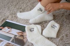 a woman sitting on the floor next to two white socks with black writing on them