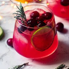 a red drink with cranberries and rosemary garnish