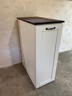 a white cabinet with a black top on the floor