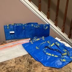 two blue bags sitting on top of a counter next to a stair case in a house