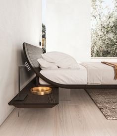 a bed sitting on top of a wooden floor next to a wall with a window